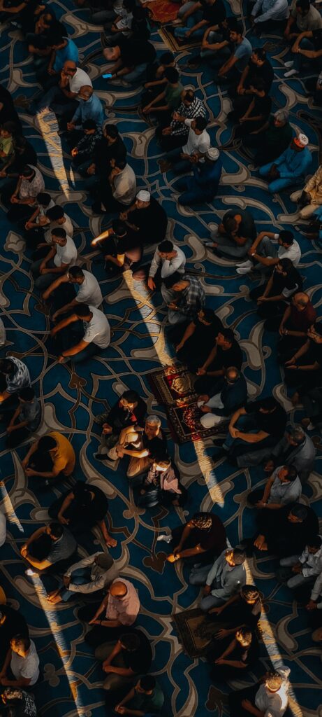 Overhead shot of a diverse group praying on a patterned carpet in a mosque.